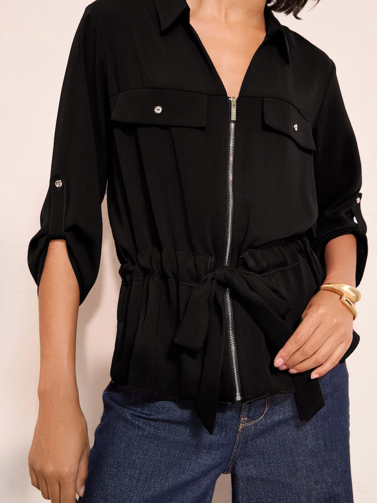 Black polyester zip front utility blouse with roll-tab sleeves chest flaps and self-fabric waist tie
