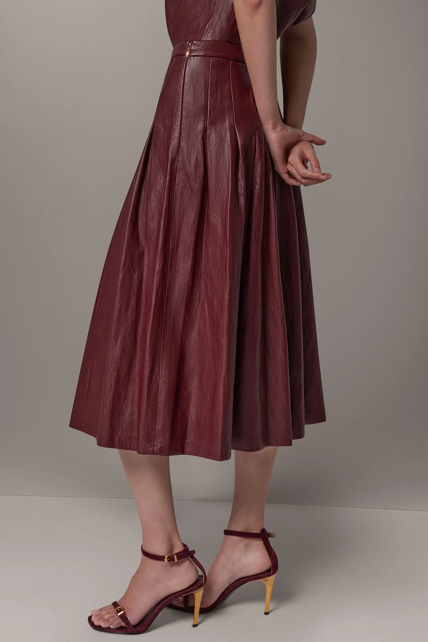 Burgundy faux leather midi skirt with stitched-down pleats and a fitted waistband