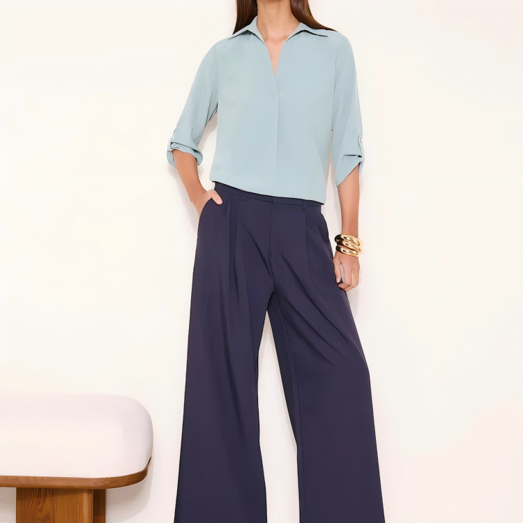 Light blue women’s collared V-neck blouse with three-quarter roll-tab sleeves and a curved back hem.