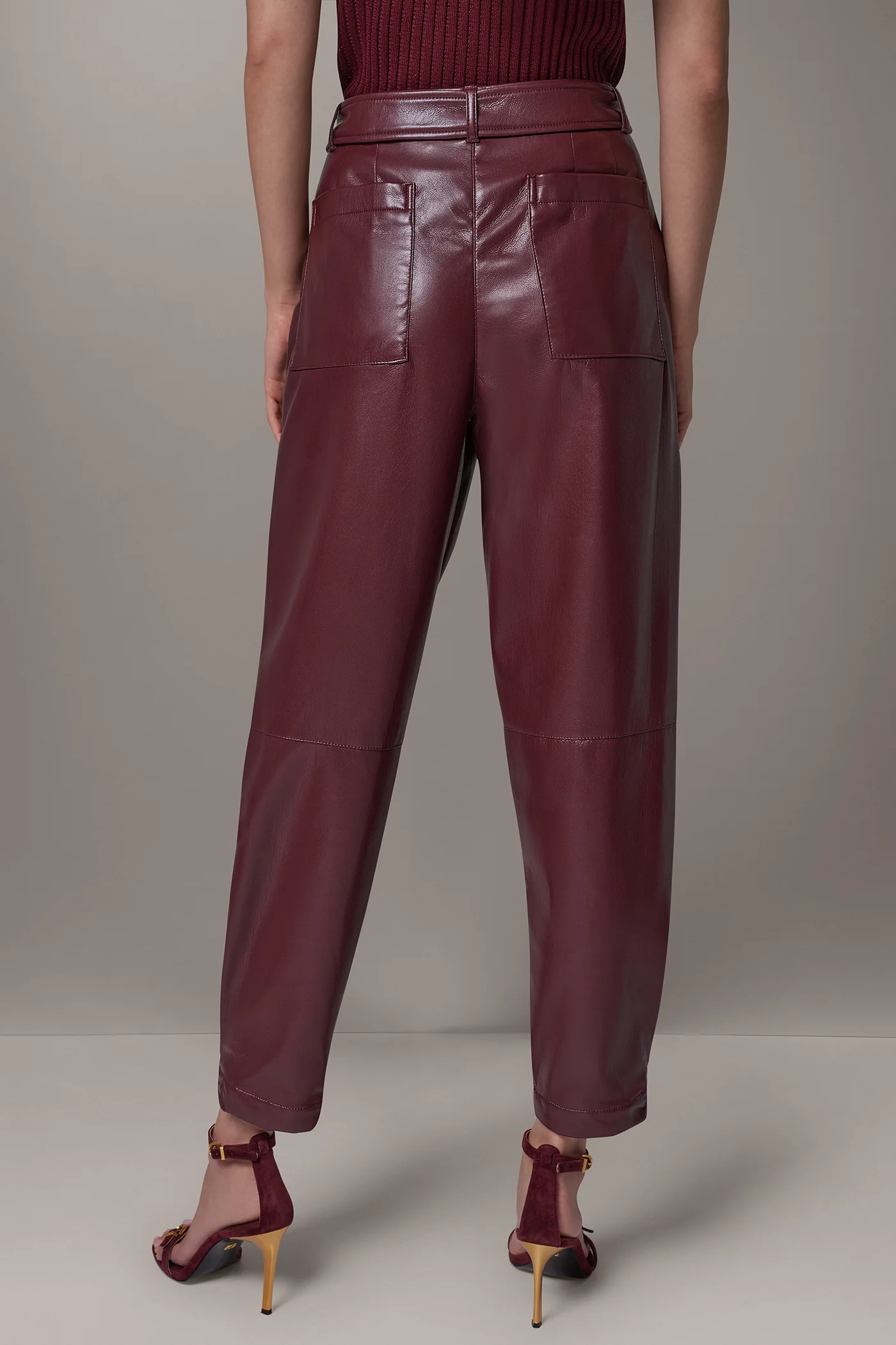 Burgundy faux leather tapered trousers with a matching belt