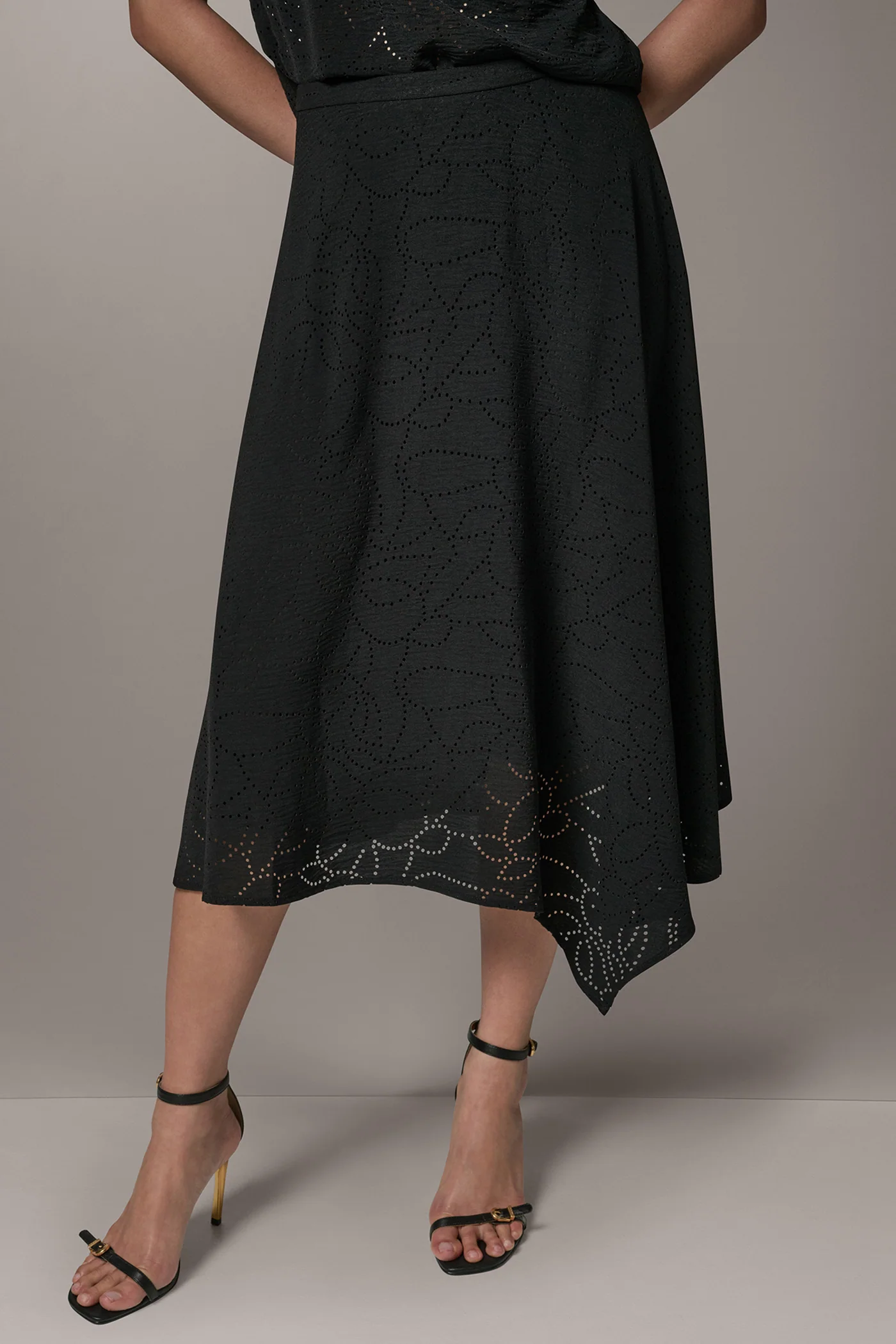 Black laser-cut A-line midi skirt with leaf motifs, an asymmetric hem and a back zipper