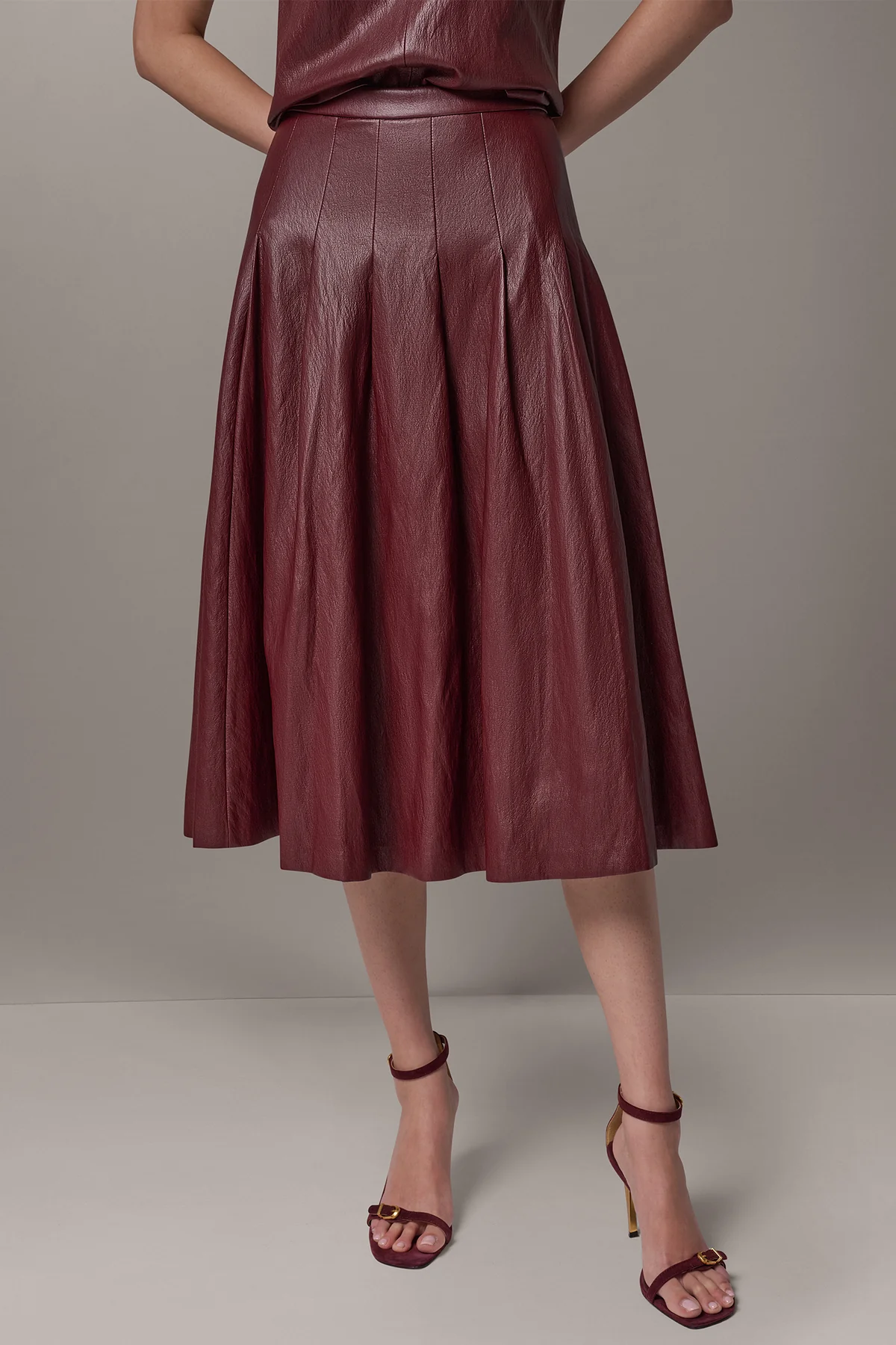Burgundy faux leather midi skirt with stitched-down pleats and a fitted waistband