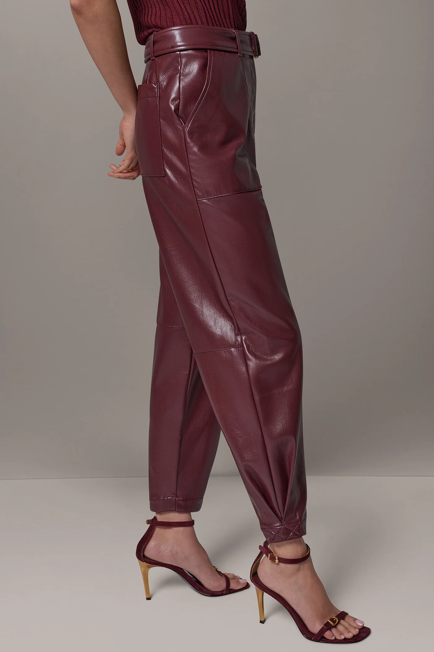 Burgundy faux leather tapered trousers with a matching belt