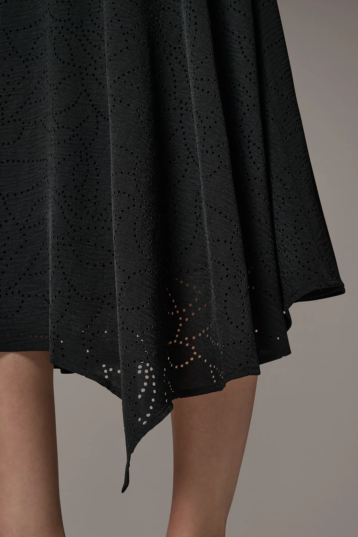 Black laser-cut A-line midi skirt with leaf motifs, an asymmetric hem and a back zipper